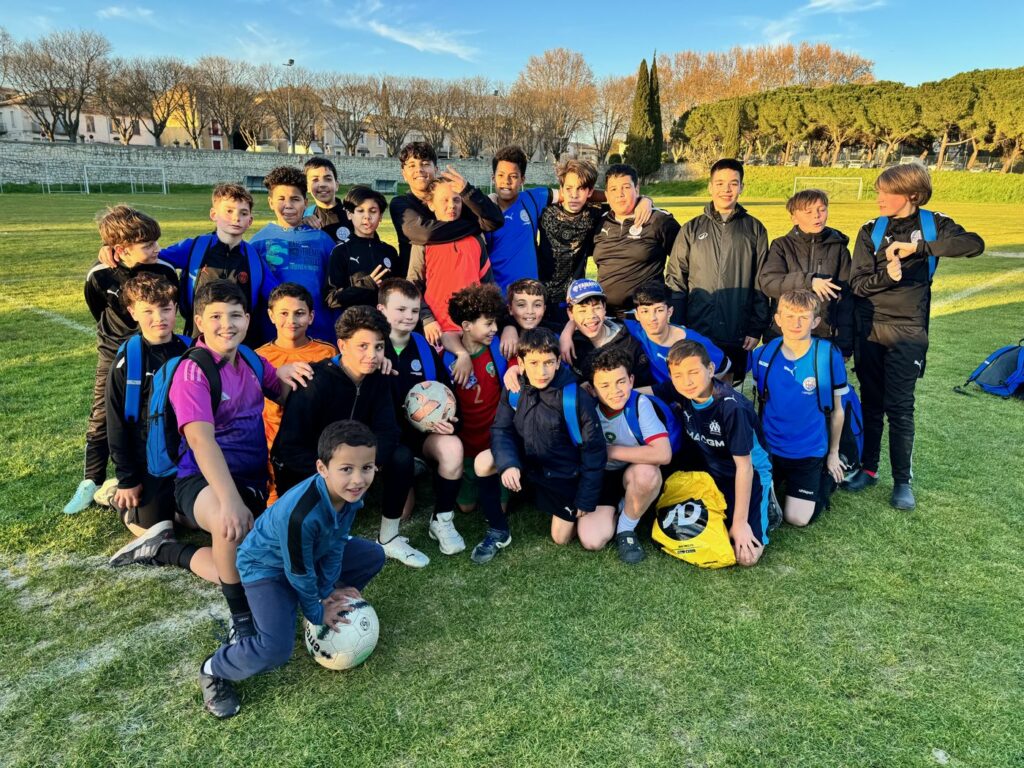 Les jeunes du Football Club Pays d'Uzès réunis sur la pelouse au coucher du soleil